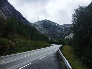 Road leading towards mountains against sky