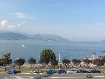 Cars on road by sea against sky