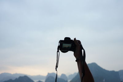 Man photographing with camera against sky