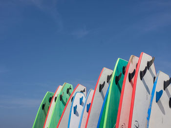 Low angle view of multi colored flags hanging against blue sky