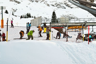 People on snow covered field against mountain