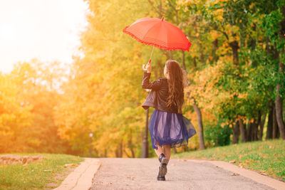 Rear view of woman holding umbrella while standing in park