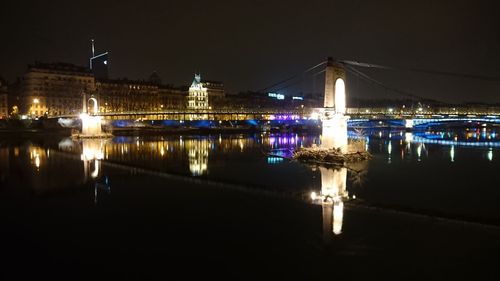 Illuminated bridge over river at night