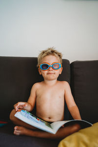 Young boy reading with goggles for homeschooling looking at the camera
