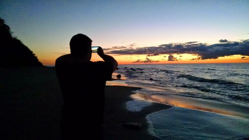 Silhouette of people on beach at sunset