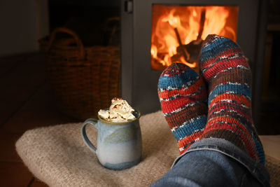 Low section of person against fireplace and by cup