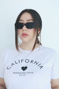 Portrait of young woman wearing sunglasses against white background