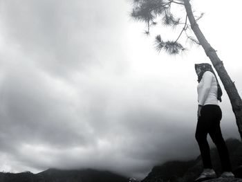 Rear view of man standing on rock against sky