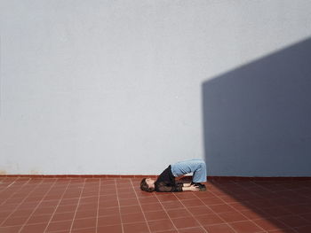 Man with umbrella on floor against wall