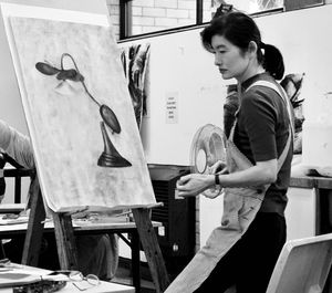 Side view of man holding painting standing at home