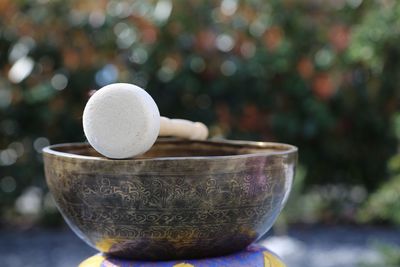 Close-up of singing bowl with mallet against natural background 