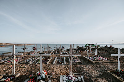 Close-up of flowers on cross by sea against sky