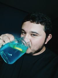 Portrait of man drinking juice in darkroom