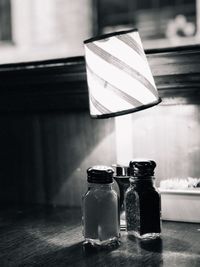 Close-up of salt and pepper shakers by illuminated lamp on table