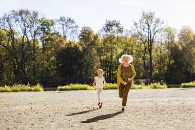 Playful senior woman running with granddaughter in park