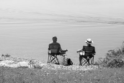 Rear view of people sitting on chair at beach