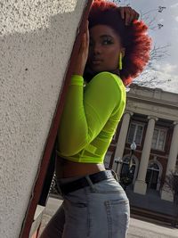 Portrait of young woman standing against wall