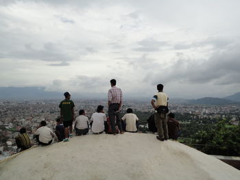 People looking at sea against sky