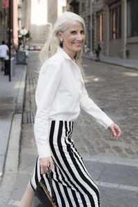 Usa, brooklyn, portrait of smiling mature woman crossing the street