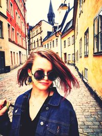 Portrait of woman in sunglasses against buildings in city
