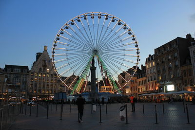 Ferris wheel in city against clear sky