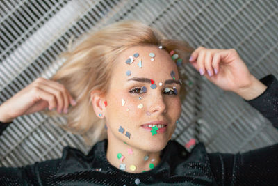 Portrait of woman with confetti on face lying on floor