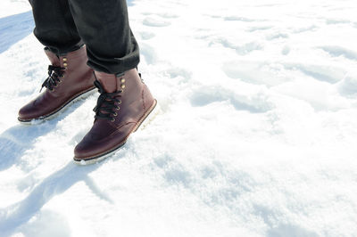 Low section of person standing on snow covered landscape