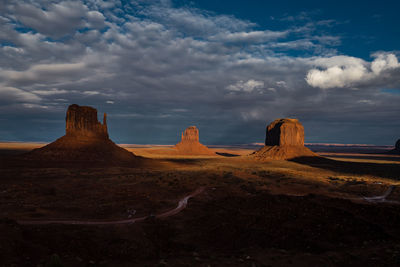 Rock formations on landscape against cloudy sky