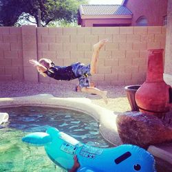 Full length side view of cute boy jumping pool