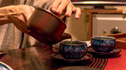 Midsection of woman holding drink at table