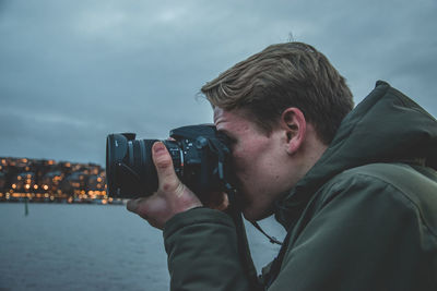 Portrait of man photographing against sky