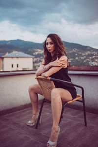 Portrait of mid adult woman sitting on chair against sky