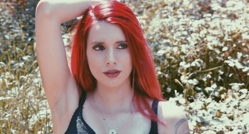 Close-up of thoughtful young woman with redhead against plants