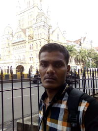 Portrait of young man standing against building in city