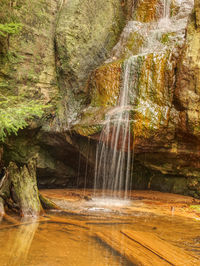 Peaceful waterfall creates a meditative mood in wilde garden. small spring on sandstone rock