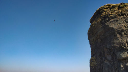 Low angle view of rock formation against clear blue sky