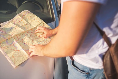 Midsection of woman with map by car