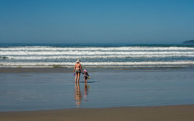 Siblings on beach against clear sky