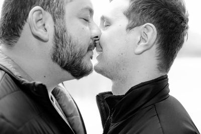 Side view of gay men kissing on mouth at park