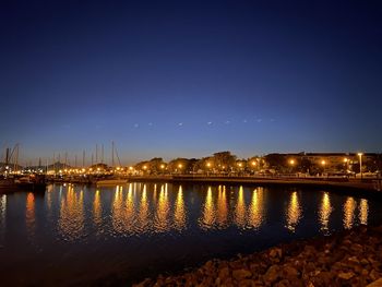 River by illuminated city against sky at night