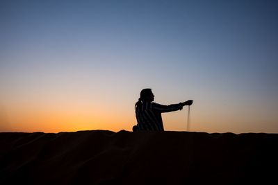 Silhouette man standing against clear sky during sunset