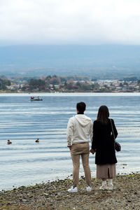 Rear view of man looking at sea against sky