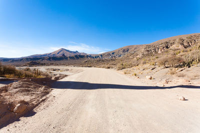 Scenic view of road by mountains against sky