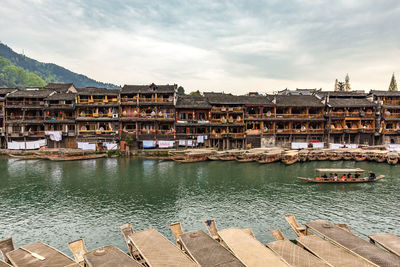 Scenic view of river by buildings against sky