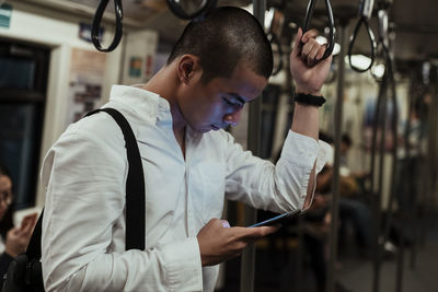 Man using smart phone while standing in train