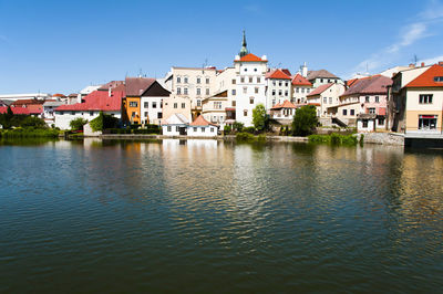 Houses by river against clear blue sky