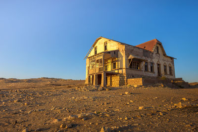 Low angle view of abandoned building against clear blue sky