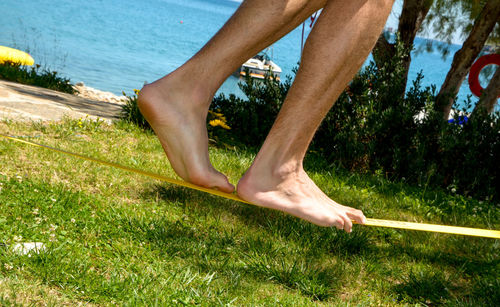Low section of man slacklining at beach