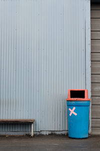 Blue garbage can against wall in building