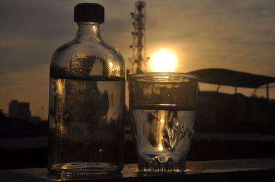 Close-up of glass bottle on table against sky during sunset